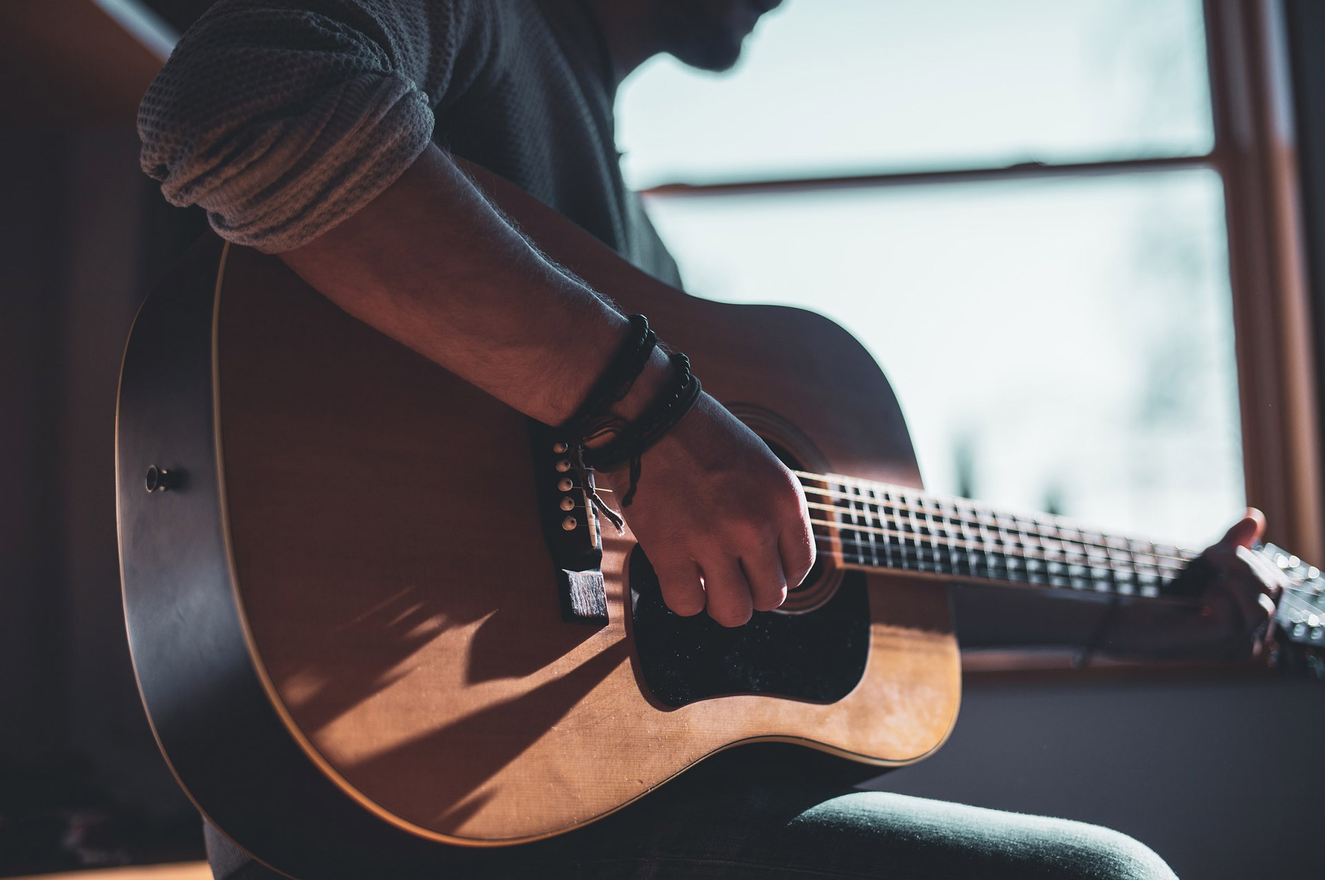 Gitarrist sitzt am Fenster. Beitragbild zum Thema Die Leidenschaft zum Beruf machen als Musiker*in selbstständig