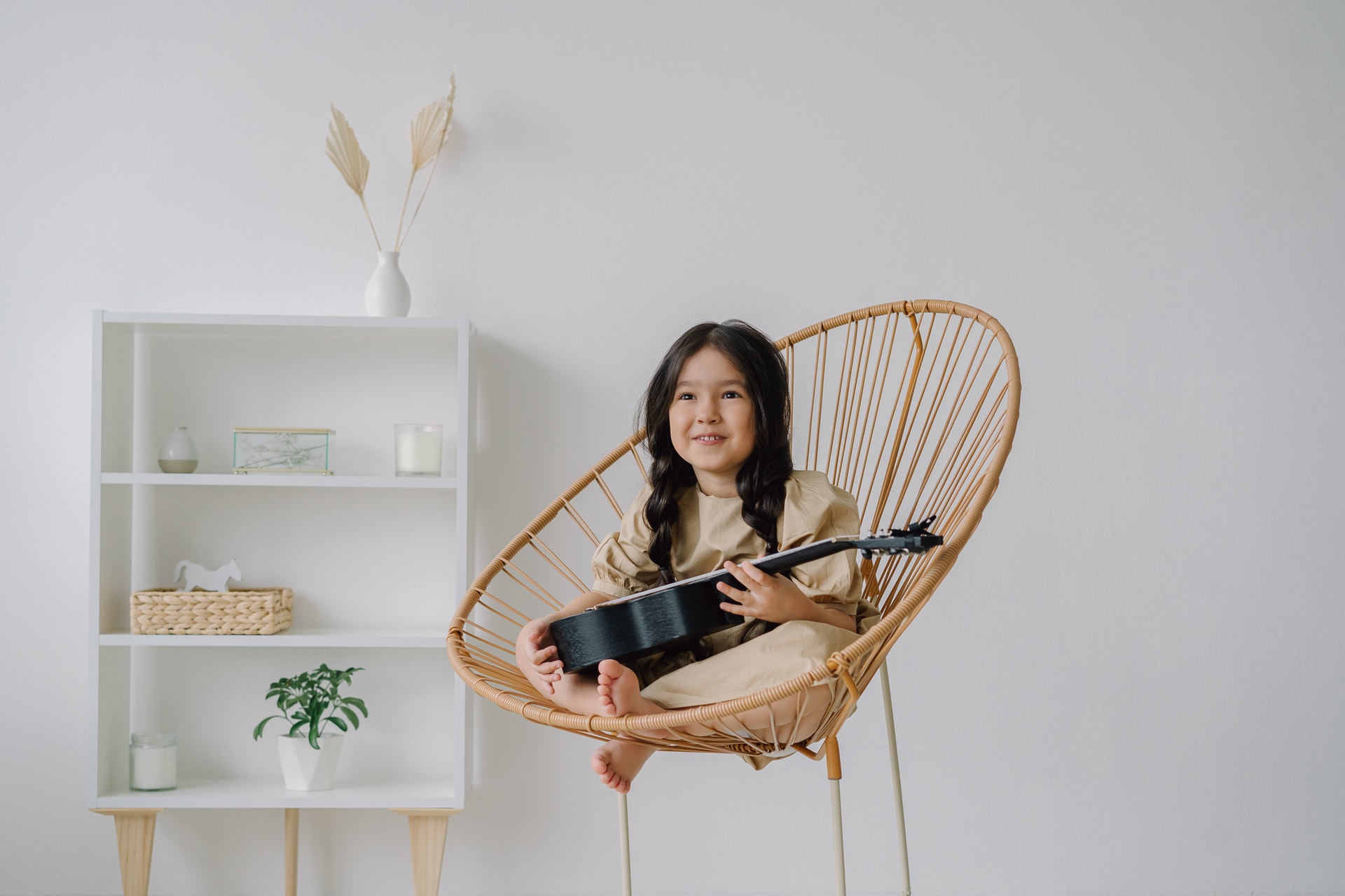 Apps zum Gitarre lernen - Kind auf Stuhl lernt Gitarre