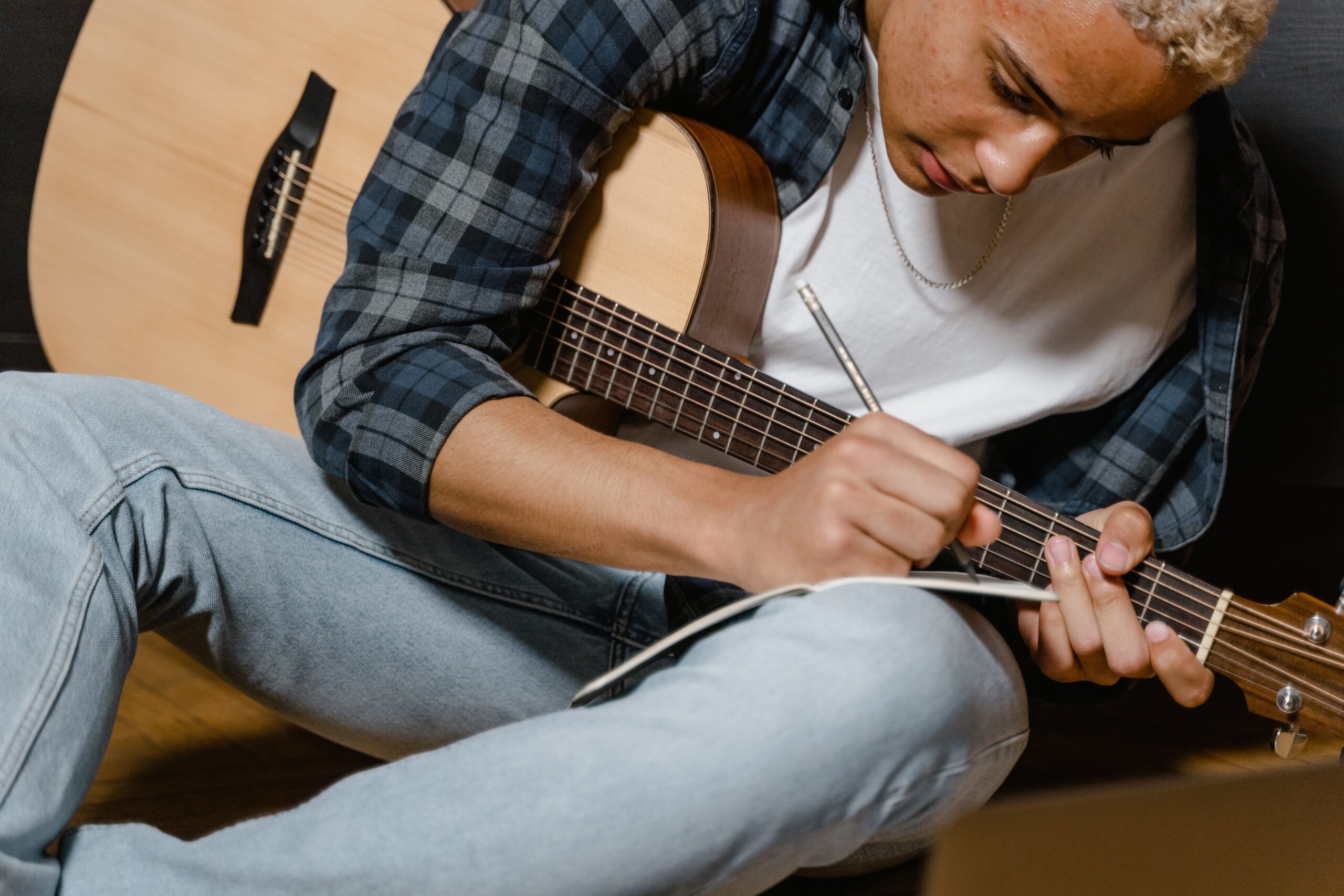 Junger Mann schreibt Musik und hat eine Gitarre in der Hand | Musik-Innovation