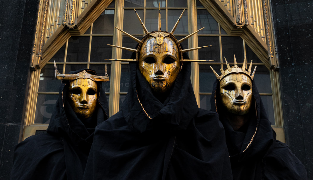 Die Band Imperial Triumphant mit goldenen Masken und schwarzen Umhängen