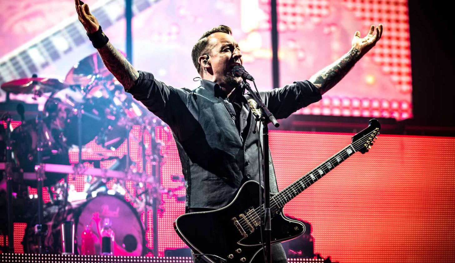 Der Sänger von Volbeat steht auf der Bühne und hat die Arme nach oben gezogen
