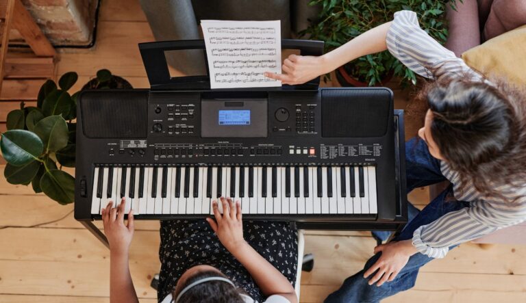 Ein junges Mädchen spielt auf einem Mini-Keyboards und wird unterrichtet