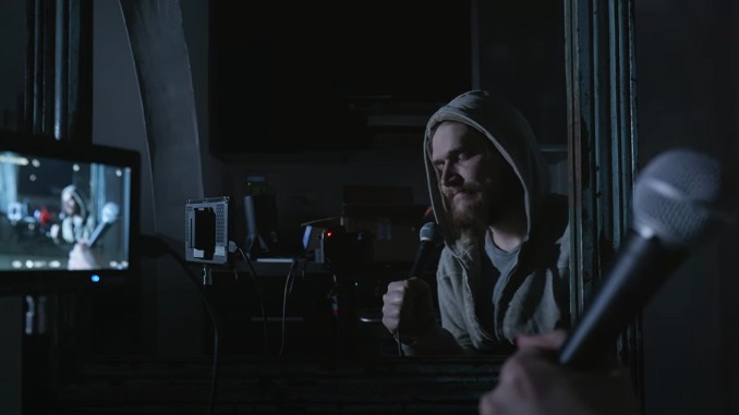 Bo Burnham sitzt mit einem Mikro vor der Kamera. Man sieht das Bild durch einen Spiegel.