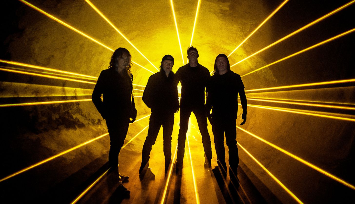 Die Band Metallica steht vor einem Strahlenmeer aus Scheinwerfern in gelb