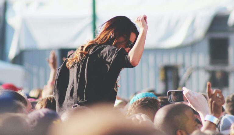 Eine Frau feiert auf den Schultern einer anderen Person auf einem Festival